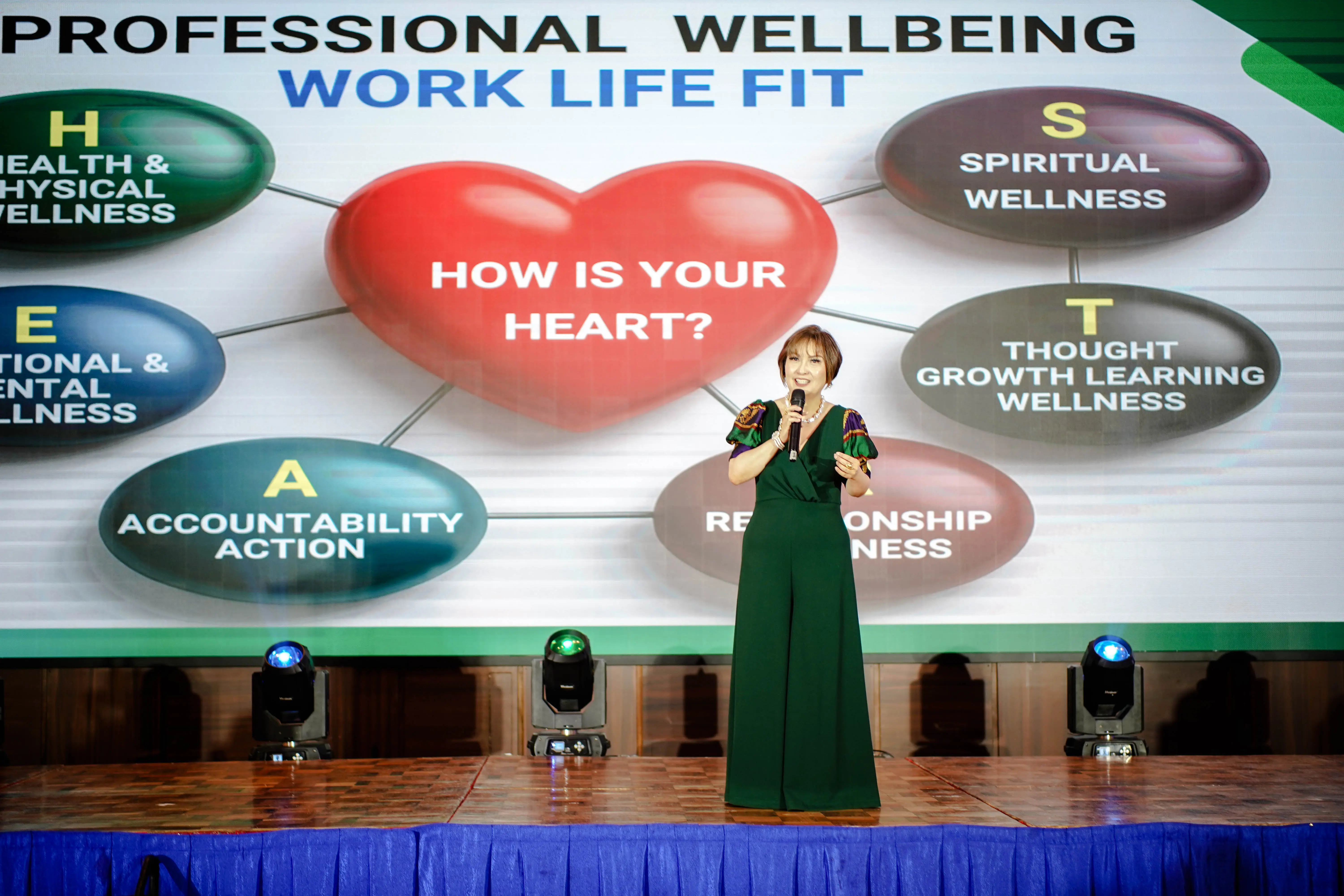 A woman in a green dress discussing a presentation on stage.