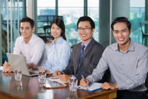 A team of executives gathered on a table and smiling infront of the camera